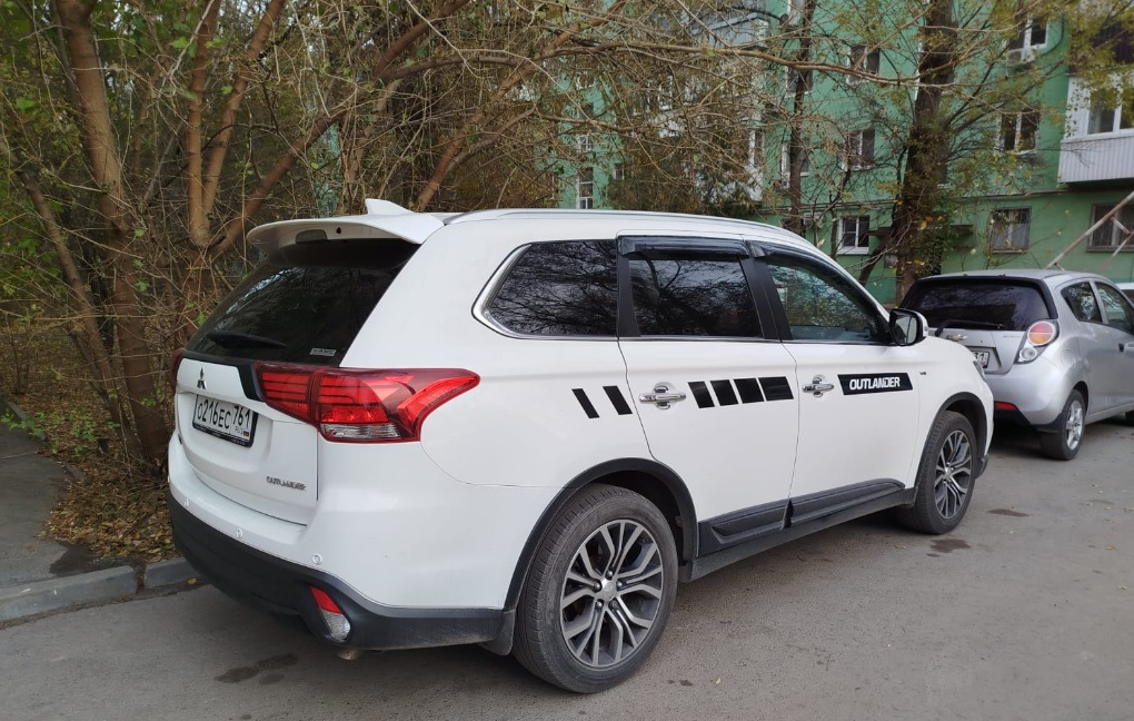 Спойлер — один из немногих элементов стайлинга для Outlander, который вызывает минимум споров — разумеется, с ним лучше, чем без него :)


Со спойлером теперь
Итак, заказал на Али сразу крашеный… По прикидкам некрашеный+покраска (зато точно в цвет) получалась примерно в 15Круб. Окрашеный сразу в белый — 4,3Круб. Решил рискнуть.

Пришел спойлер в транспортную компанию упакованный в пузырчатую пленку основательно, как мумия :)
И, тем не менее — сурпрыз! Заметный залом на внешнем ребре :(


Ну как так?
Ну в той 10-сантиметровой толщины обертке вряд ли так могло получиться, скорее всего сразу таким положили.
В-общем, подал спор (изначально подумал, что оспоренный деньги отдам мастерам, чтобы шпатлевали и красили). Отспорил 1,8Круб. То есть спойлер с дефектом обошелся в 2,5Круб.


По цвету — очень хорошее попадание, разве что на спойлере есть примесь блестящая (наверное, это Polar White или как его там). Но с завода бампера от кузова отличаются существенно сильнее :)
Уже начал у знакомых спрашивать, кто занимается такими работами, никто не признавался… повертел-покрутил в руках и решил кое-что попробовать :)

Сделал технологическое отверстие на внутренней стороне, обмотал изолентой наконечник длинной отвертки, нагрел спойлер в теплой воде, арендовал у жены фен и поставил его на минимальный нагрев.
Ну и изнутри минут за 30 осторожненько выровнял дефект.


Технологическое отверстие и инструмент
Пару недель спойлер отлежался на балконе (проверил, не сработает ли эффект памяти у пластика, когда остынет). Дефект проявился прям минимально (и то, это я знал, куда смотреть). Еще минут 10 повторил процедуру поддавливания и нагрева — и вуаля! Результат отличный.


Живьем вообще место дефекта не найдешь
Следующим квестом оказалось прикрепление.
Дальнейший текст скорее всего будет более интересен ростовчанам…

Беглый поиск стекольного герметика и праймера показал, что это добро обойдется в пару тысяч, не меньше. И потом почти весь герметик все равно на выброс…
Заехал в пару мест, где устанавливают стекла. В одном (федеральная сетка, АвтоТрейд) сразу сказали, что у них нет такой услуги в прайсе, а "внепрайсовые работы" караются штрафом и вплоть до увольнения. Но общались вежливо.

В другом (с довольно живыми социальными сетями, вроде как позиционирующие себя положительно, Автостекла на Вавилова) — просто вышел чувак, ни здрасте, ни досвидания, просто сказал "нет, я это делать не буду" и развернулся. Резкий контраст с социальными сетями. Неприятный осадочек :)

Уже подумал — ну всё, придется самому материалы покупать и звать кого-нибудь на помощь для ровной установки. Но решил заглянуть к еще одним установщикам автостекол. Оказалось, неподалеку есть AG Experts. Ребята красавчики — и пообщались вежливо, и один парень вышел посмотрел-пощупал спойлер. Согласились сделать. Подошли прям очень профессионально — все обезжирили, нанесли праймер, погрели феном и спойлер и крышку багажника, нанесли герметик, приклеили спойлер. И стоимость услуги нормальная — 1,5Круб.


Кепка
В-общем, теперь Белый Бумбр со спойлером.
Считаю, что он делает внешний вид аута существенно гармоничнее. Плюс стоимость доработки получилась ну очень приятной.