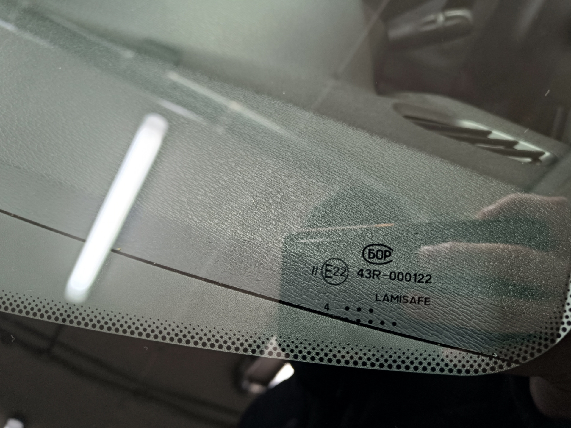 В общем, машина стояла на улице весь ноябрь. Приехал с командировки и утром завёл, а сам пошел домой пить чай пока она грелась. Через пол часа выхожу и вижу, что по всей длине лобовой появилась трещина от небольшого скола — поймал камушек летом, когда ехал на море.

Трещина на всю длину. Стекло SISECAM
Вроде особо и не мешается, но напрягало, что находится на уровне глаз. Так покатался где-то месяц и решил позвонить нескольким фирмам, так сказать узнать цены рынка. Первой фирмой оказалась AG Experts. Цену за стандартное стекло Бор с небольшим затемнением и зелёным оттенком озвучили 7800 рублей. Установка бесплатная. После этого даже звонить не стал другим фирмам, а сразу записался на удобную дату — цена меня устроила. Во время разговора уточнил ещё раз нужную модель стекла с евро-кодом 4592AGS и переспросил точно будет оригинальный Бор, а не какой-то кооператив… Ответили, что будет 100% Бор, который сейчас ставят на конвейер, надо только выбрать вариант его исполнения: с датчиками или без, и т.п. Попросили в день установки заранее заехать на мойку.

А вот и мойка. Прайс — космос для Уфы, одна фаза 600 рублей 🙂 и это только наружка…
После мойки заехал в соседний бокс, где уже весёлые ребята за несколько минут разобрали жабо и сняли старое лобовое.

Старое заводское стекло SISECAM
На фото видно тот самый скол, с которого всё пошло по швам…

Парни срезали лишний герметик и обезжирили поверхность
Видно, что на заводе особо не заморачиваются и наносят герметик так себе. Теперь понятно, почему у некоторых владельцев вода в салоне: на фото можно найти уязвимые места.

Новое стекло установлено. Теперь у нас Бор.
Пол часа и готово!

Стекло ветровое Бор 8450007323 E22 43R-000122 Lamisafe
После того как приклеили, я ещё часик погулял в ближайшем ТЦ пока схватится герметик, вернулся и успел пообщаться с мастерами. Прошло 2 часа и я не спеша поехал домой.

P.s. Парни сказали, что стекла AGS и Бор делают в одном заводе, чему я был удивлён.